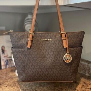 Michael Kors chocolate monogram hand bag, and brown tri-fold wallet.